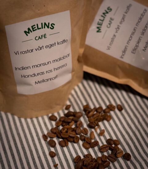 Två påsar med Melins egenrostade kaffe och utspridda kaffebönor